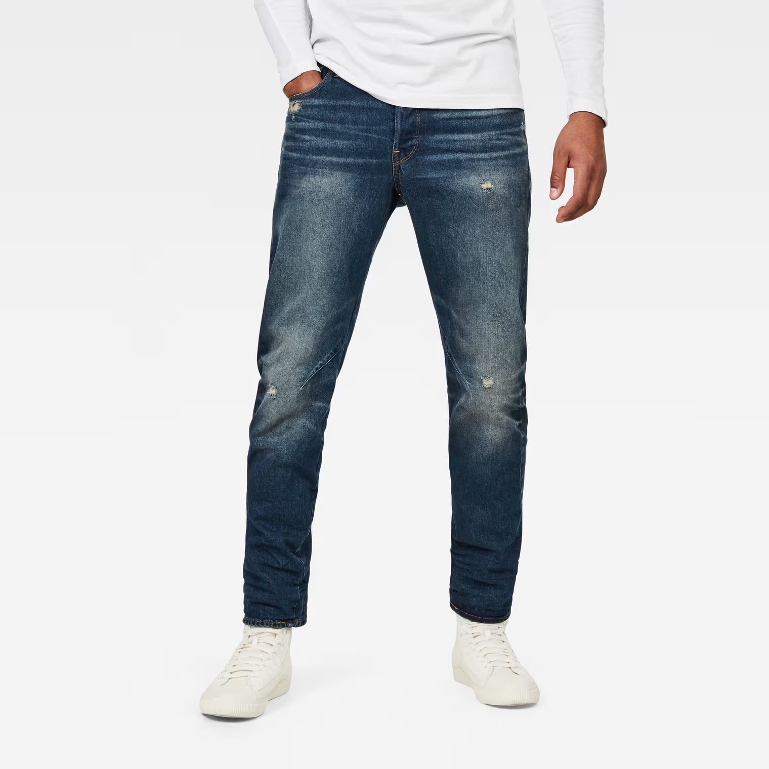 Lifestyle shot of dark blue jeans featuring a relaxed fit and tapered leg on a white background.