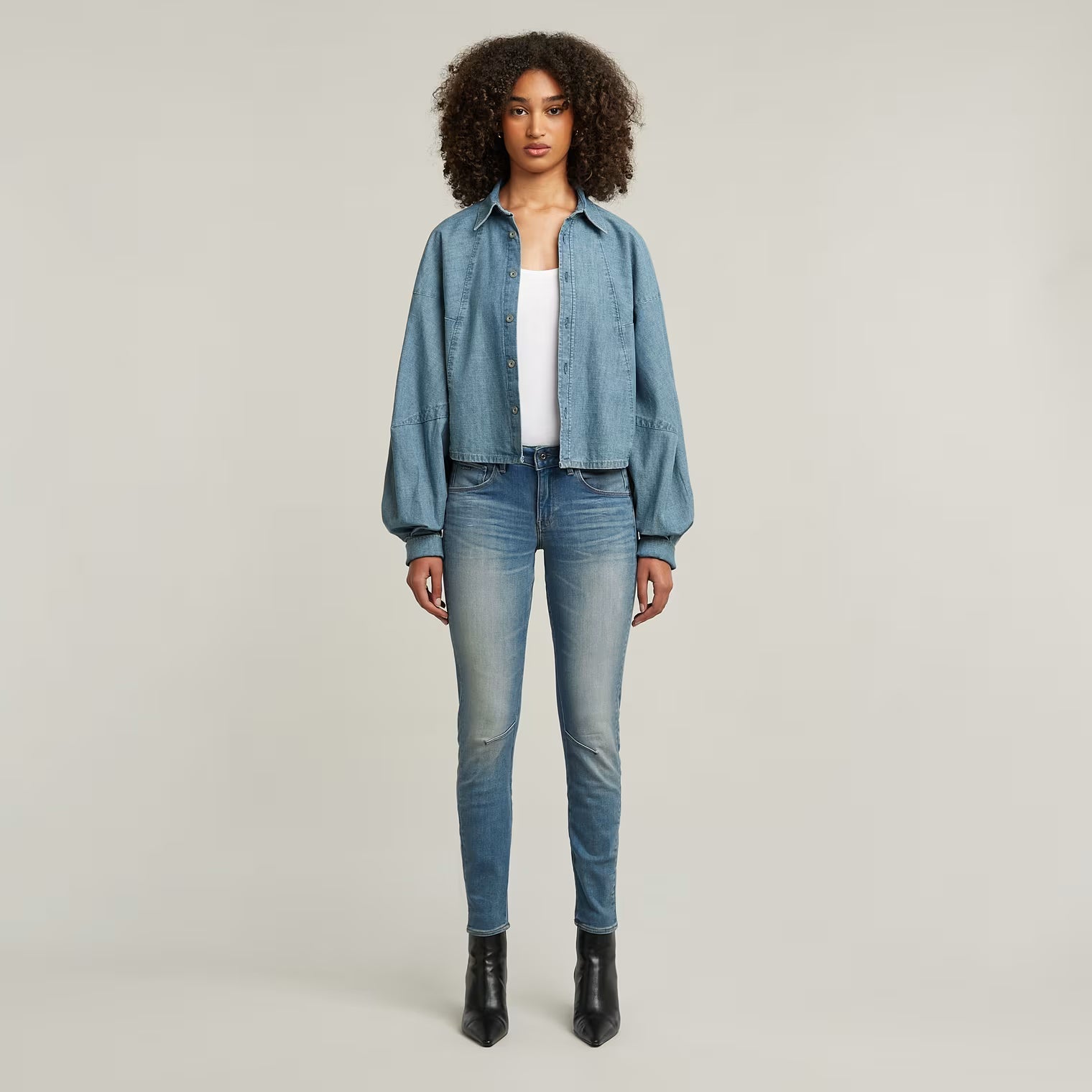 Lifestyle shot of a model wearing blue skinny jeans with a faded design and slim fit.