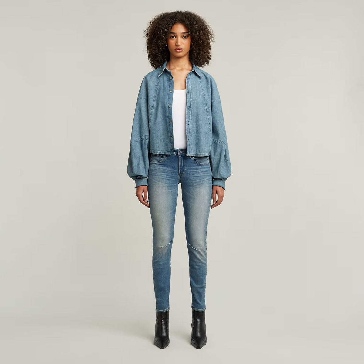 Lifestyle shot of a model wearing blue skinny jeans with a faded design and slim fit.