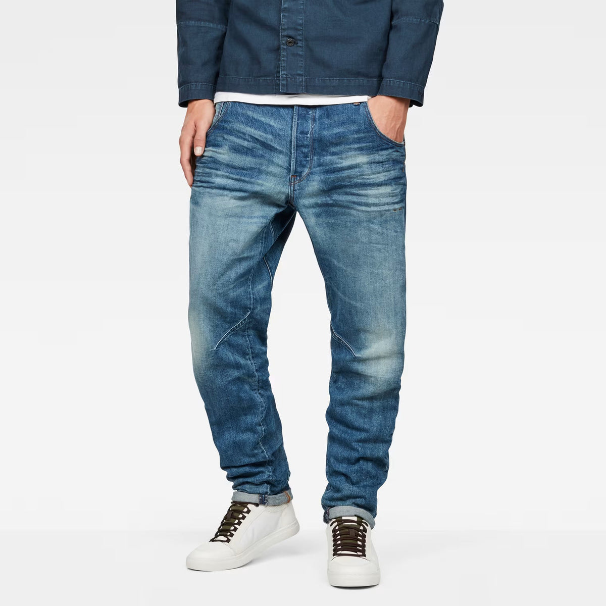 Lifestyle shot of medium blue tapered jeans featuring distressed details and a slim fit.