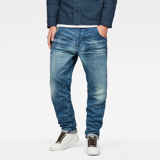 Lifestyle shot of medium blue tapered jeans featuring distressed details and a slim fit.