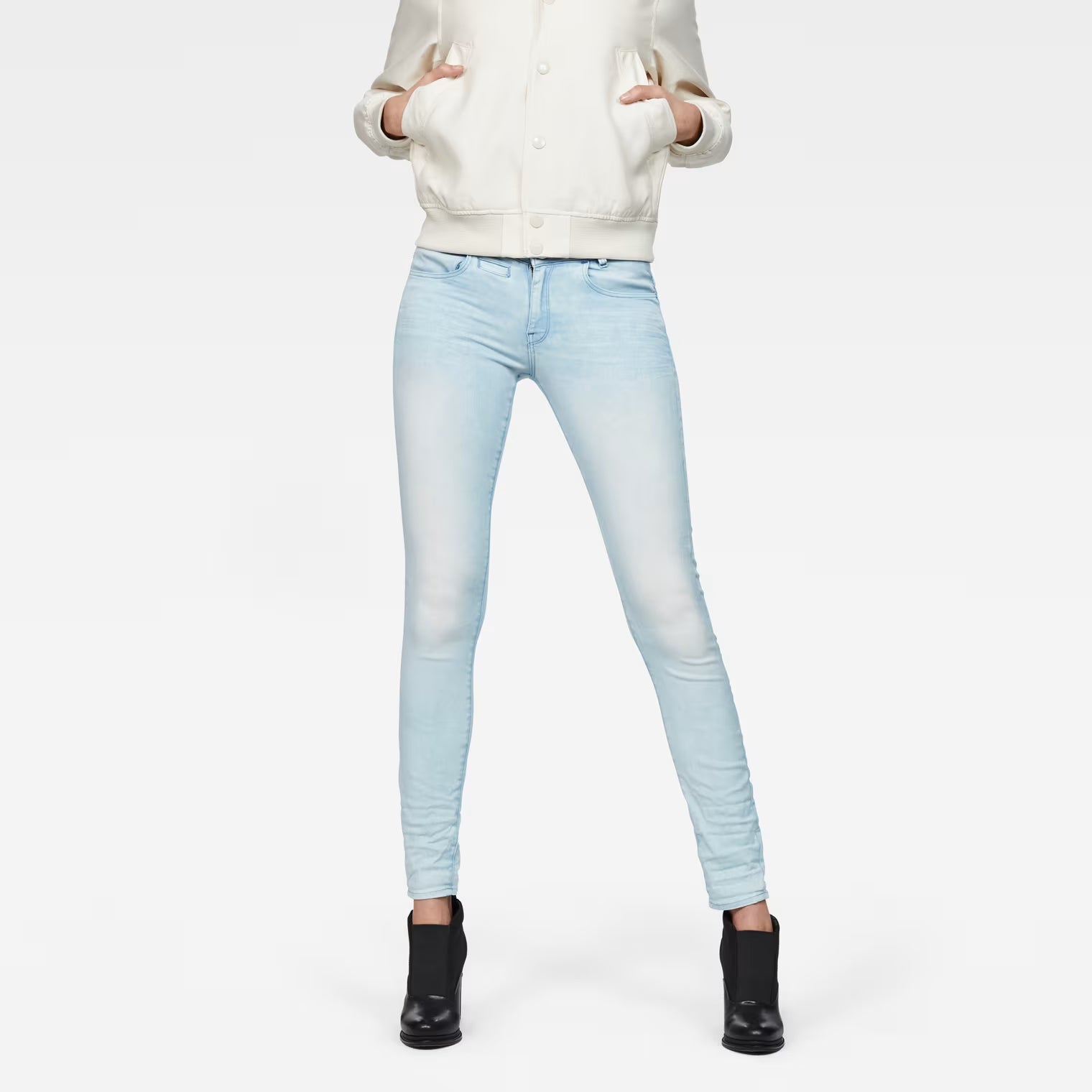Lifestyle shot of light blue skinny jeans featuring a 5-pocket design against a white background.