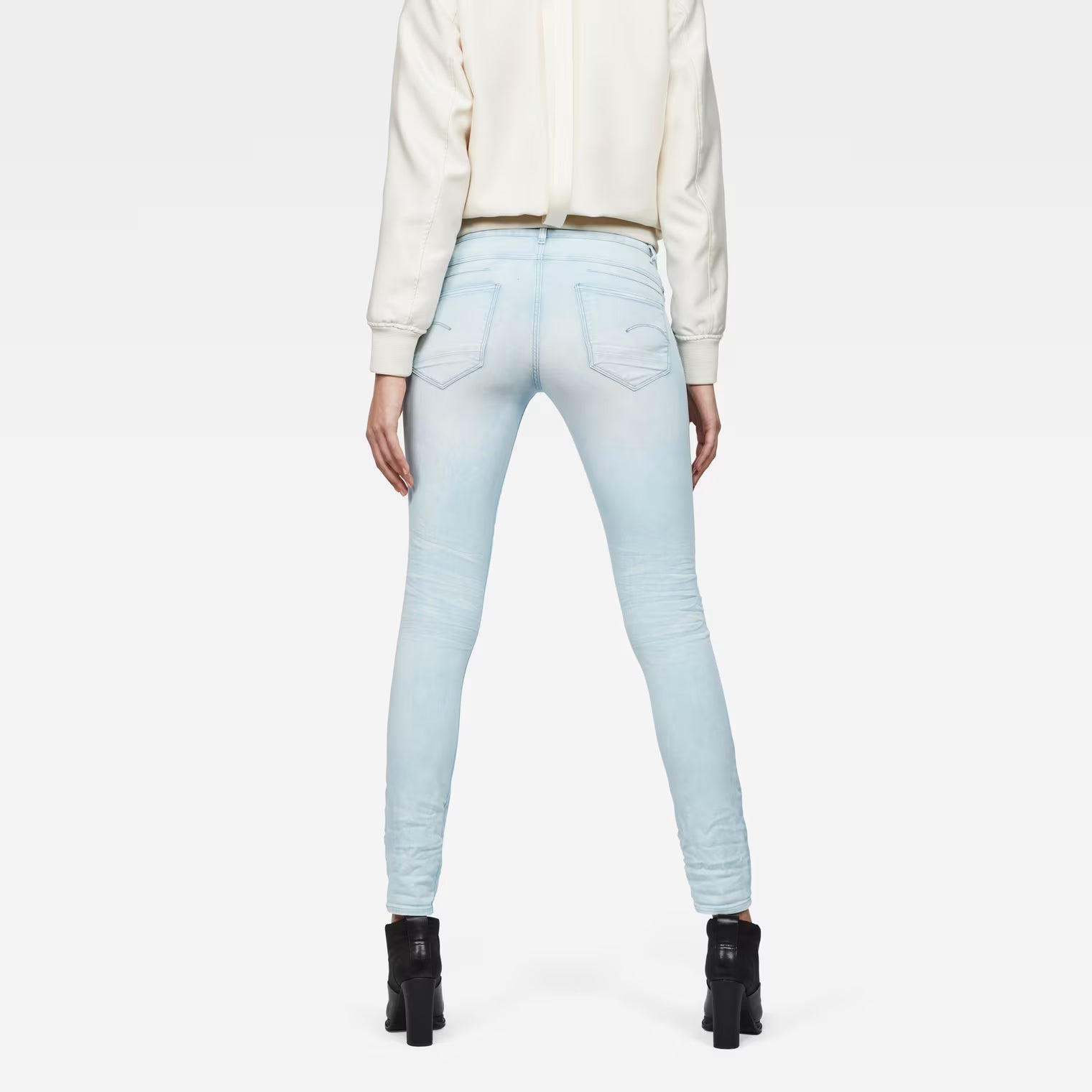 Back view of light blue skinny jeans showcasing the 5-pocket design on a white background.