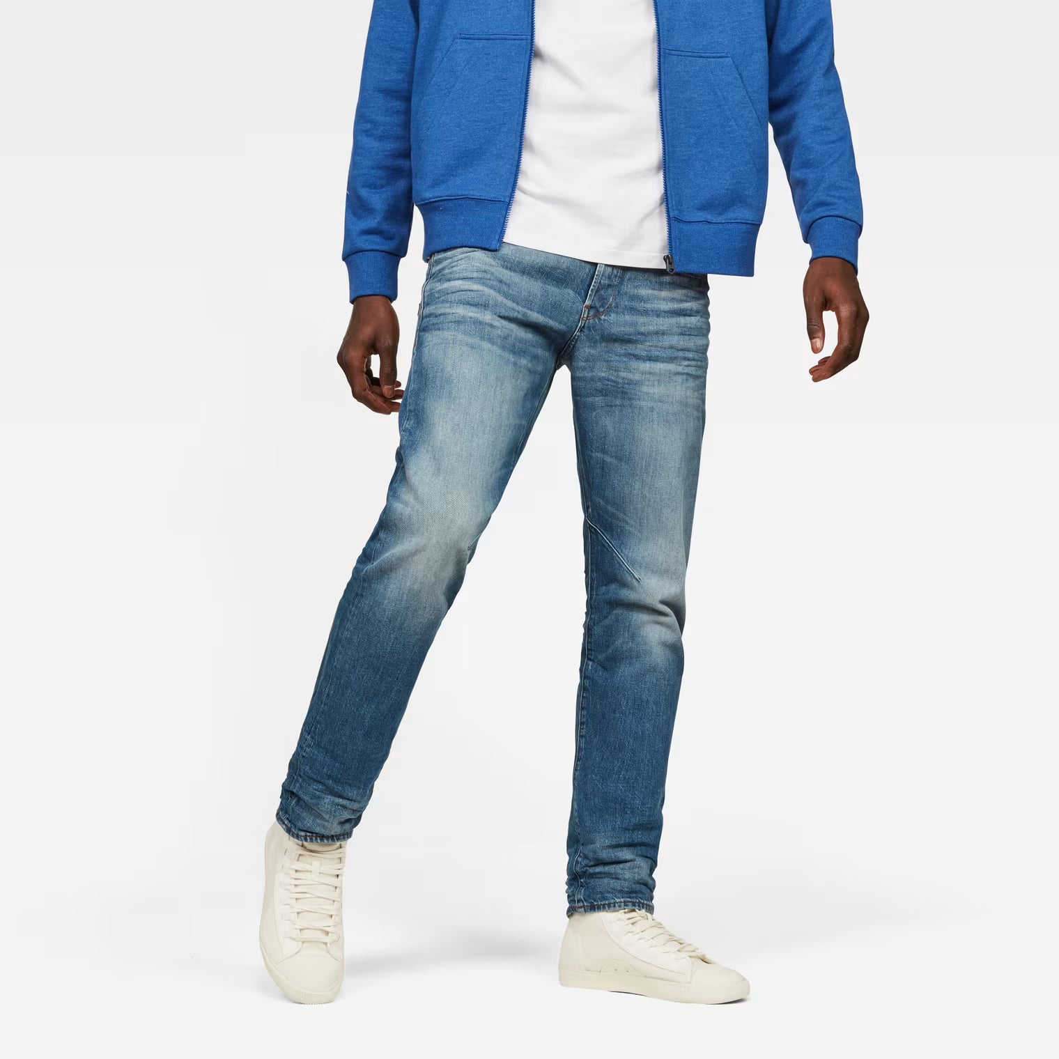 Lifestyle shot of tapered blue jeans featuring a 5-pocket design on a white background.