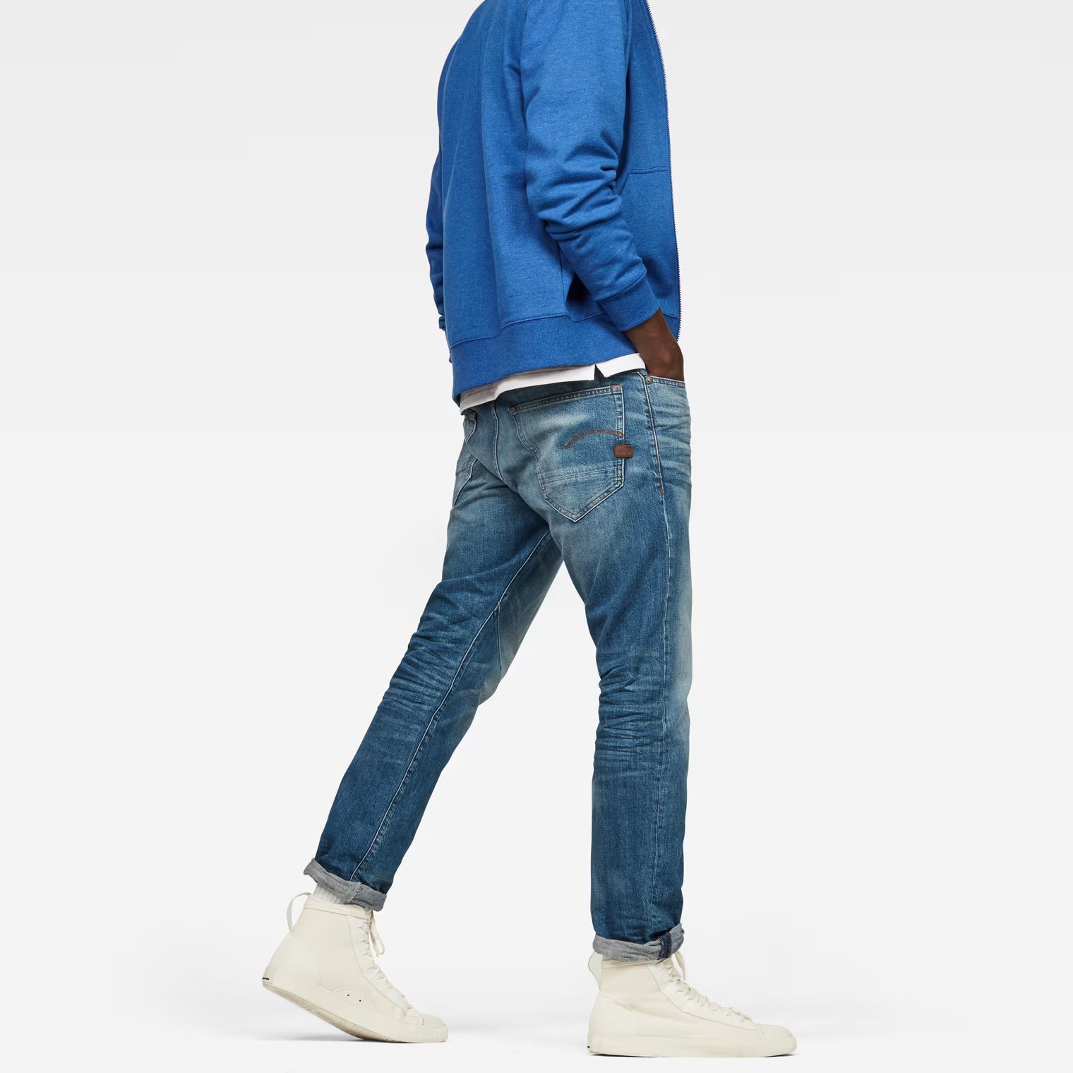 Side view of tapered blue jeans showcasing a 5-pocket design against a white backdrop.
