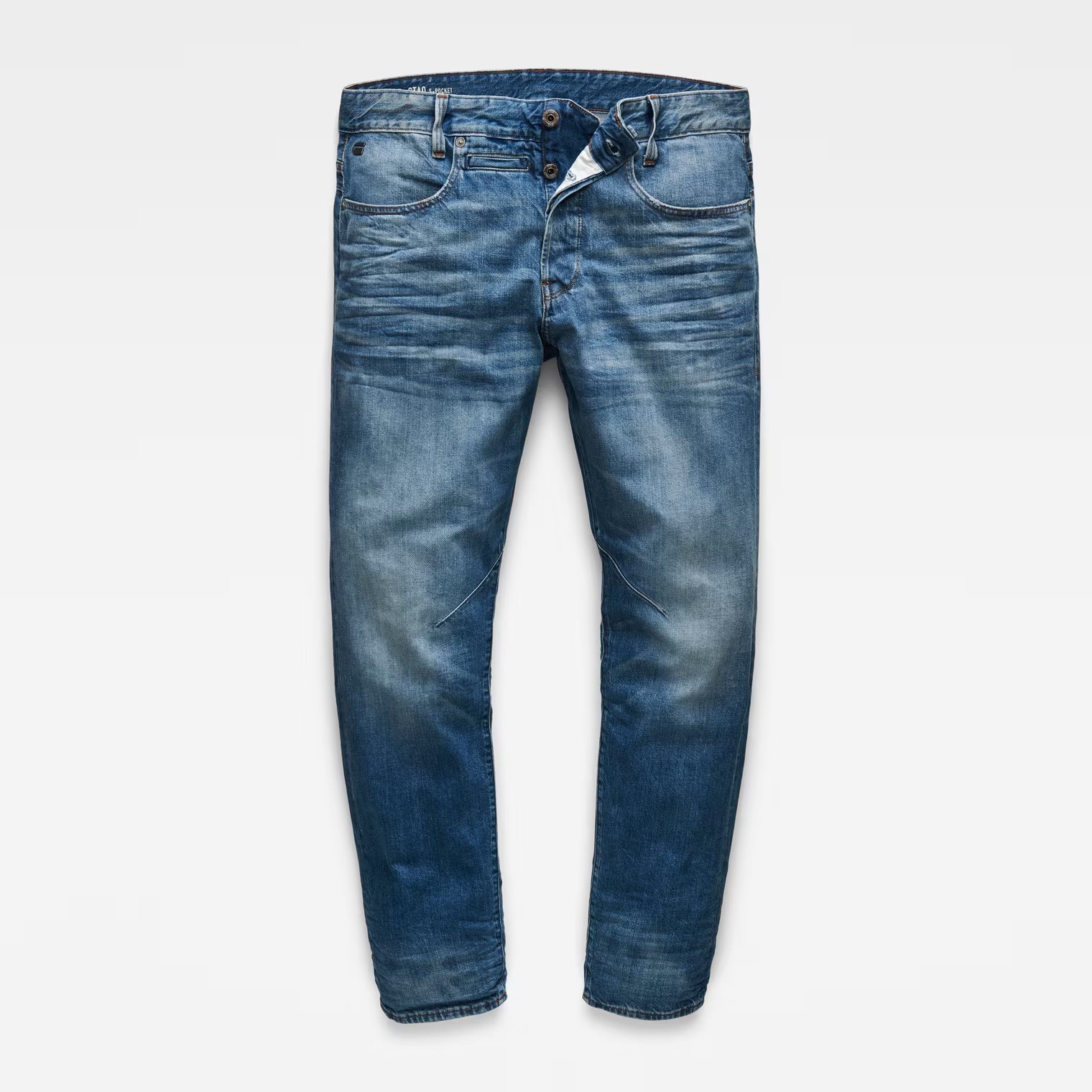 Front view of tapered blue jeans in medium wash with a 5-pocket design on a white background.