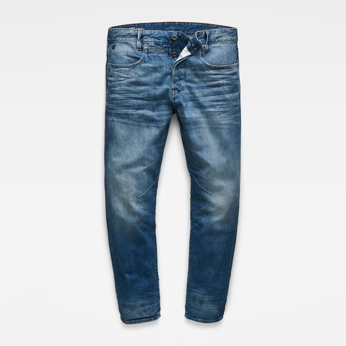 Front view of tapered blue jeans in medium wash with a 5-pocket design on a white background.