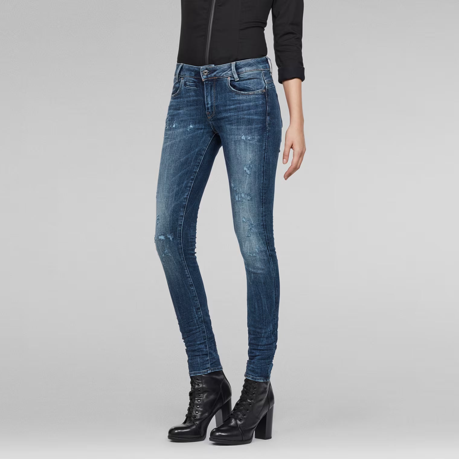 Side view of medium blue skinny jeans featuring a mid waist design.