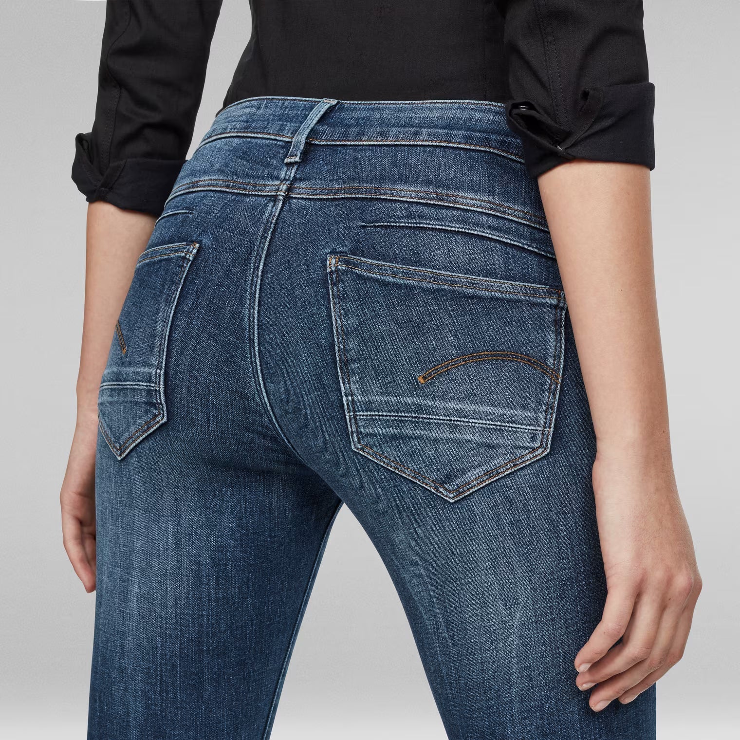 Detail shot of medium blue skinny jeans showing back pockets.