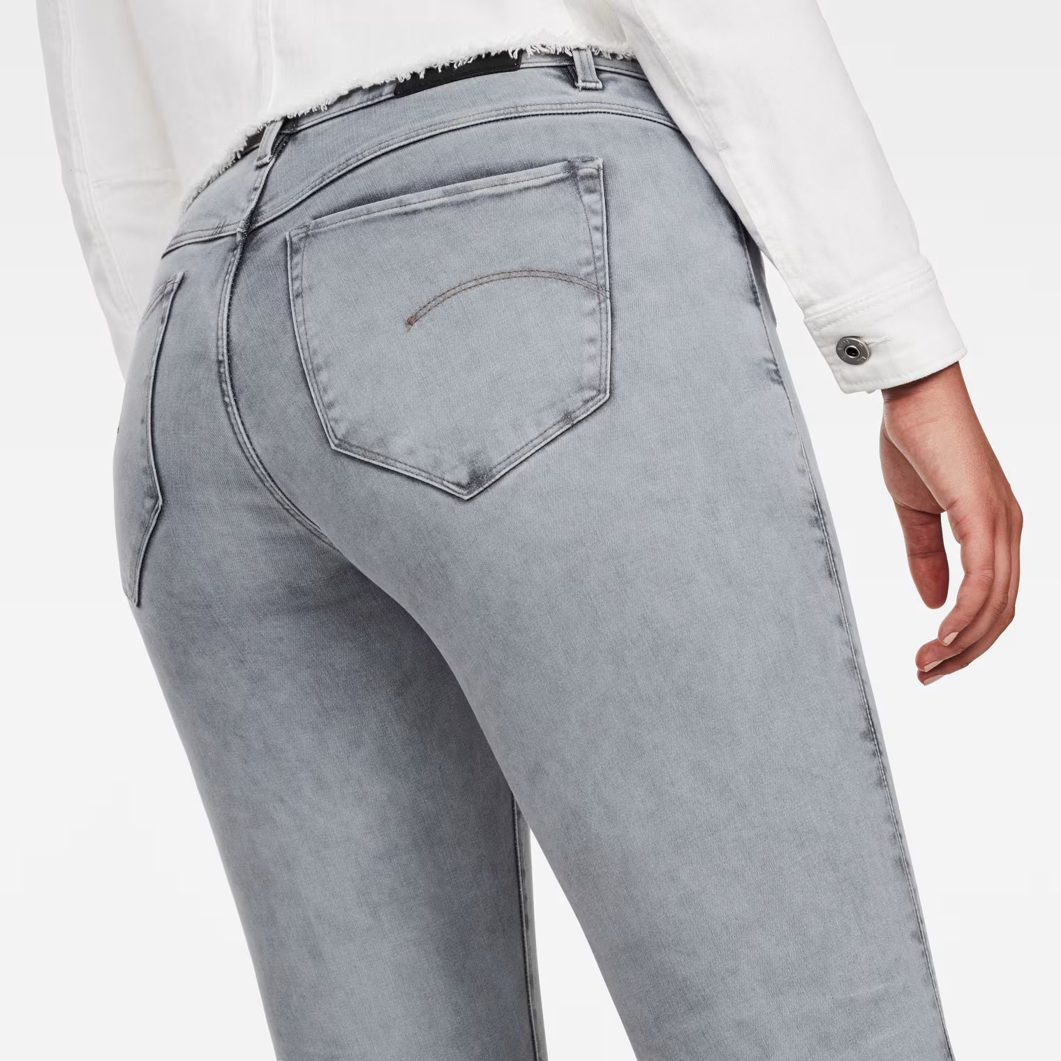 Detail close-up of light blue skinny jeans highlighting the back pockets and high waist.