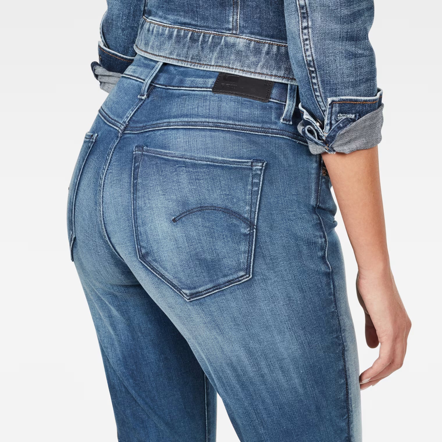 Detail close-up of medium blue skinny jeans highlighting back pocket design and faded areas.