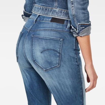 Detail close-up of medium blue skinny jeans highlighting back pocket design and faded areas.