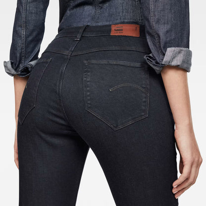 Detail shot of black skinny jeans highlighting back pockets and high waist on a white background.