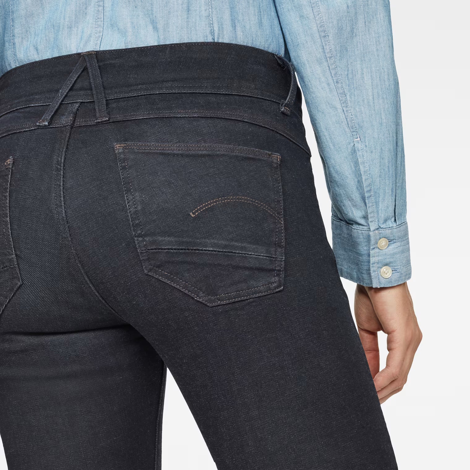 Detail close-up of black super skinny jeans showing back pockets on a white background.