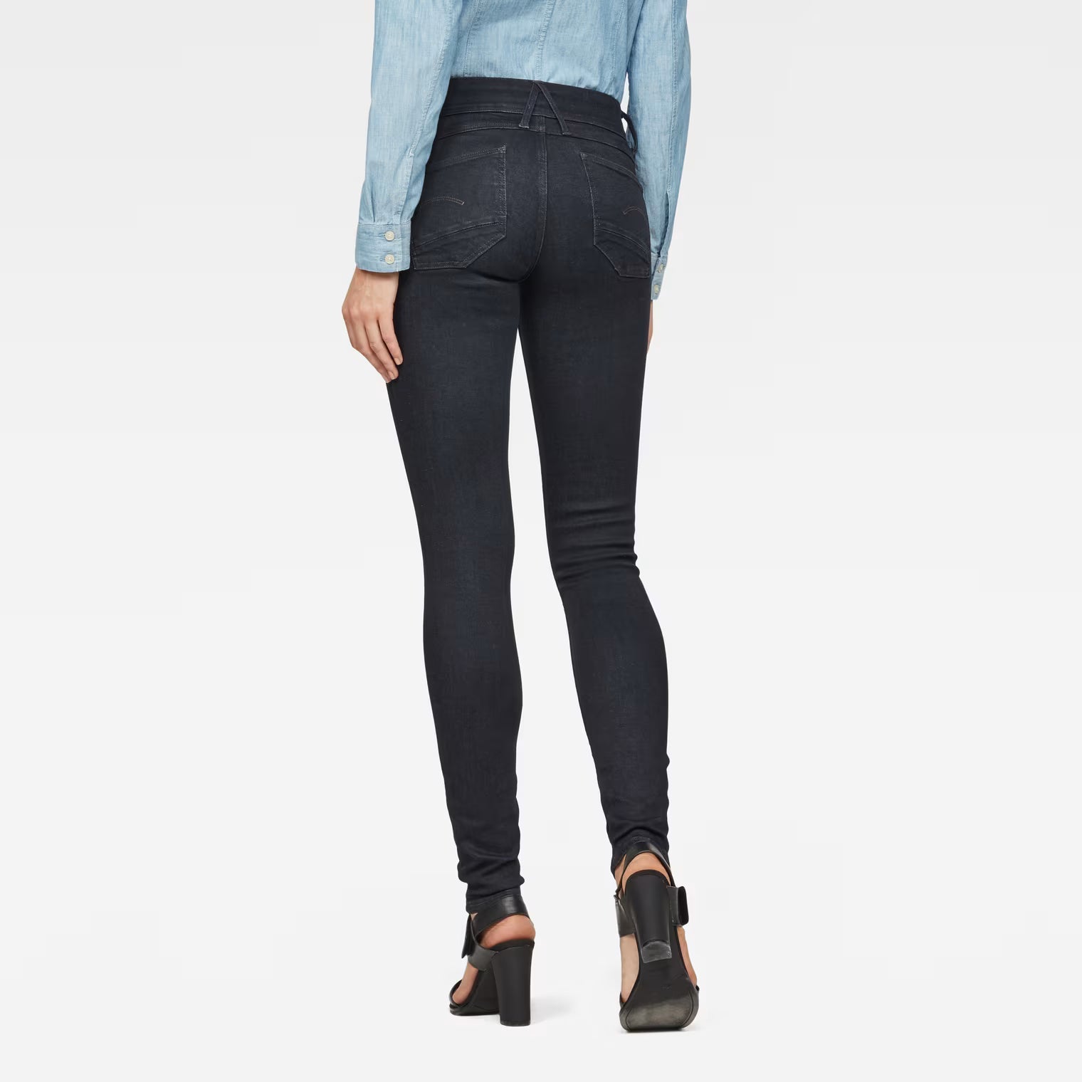 Back view of black super skinny jeans featuring a mid-rise fit on a white background.