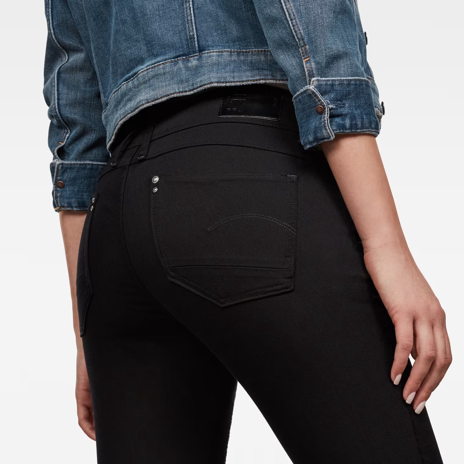 Detail close-up of the back pocket on black skinny jeans with a skinny fit.