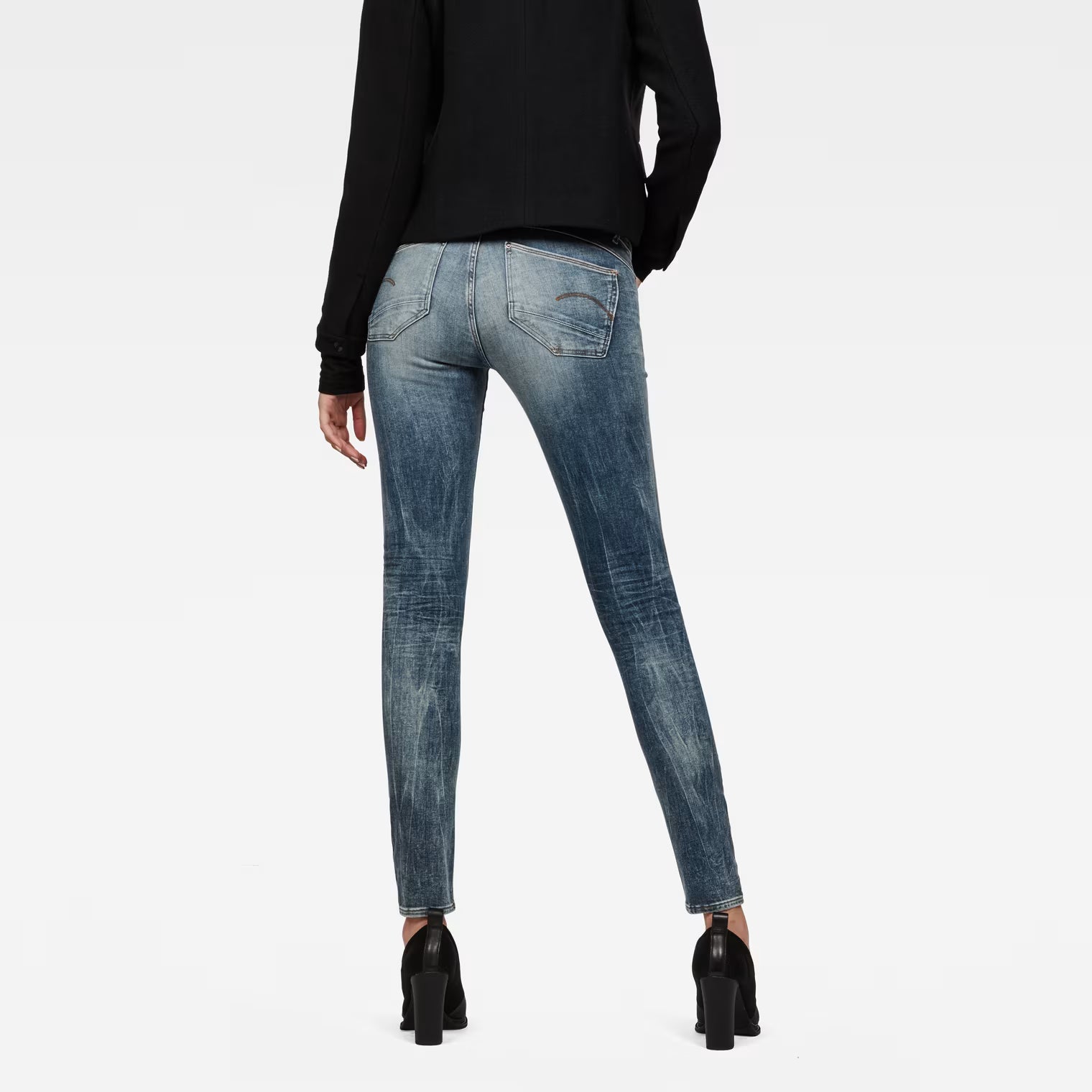 Back view of light blue skinny jeans featuring a mid waist on a white background