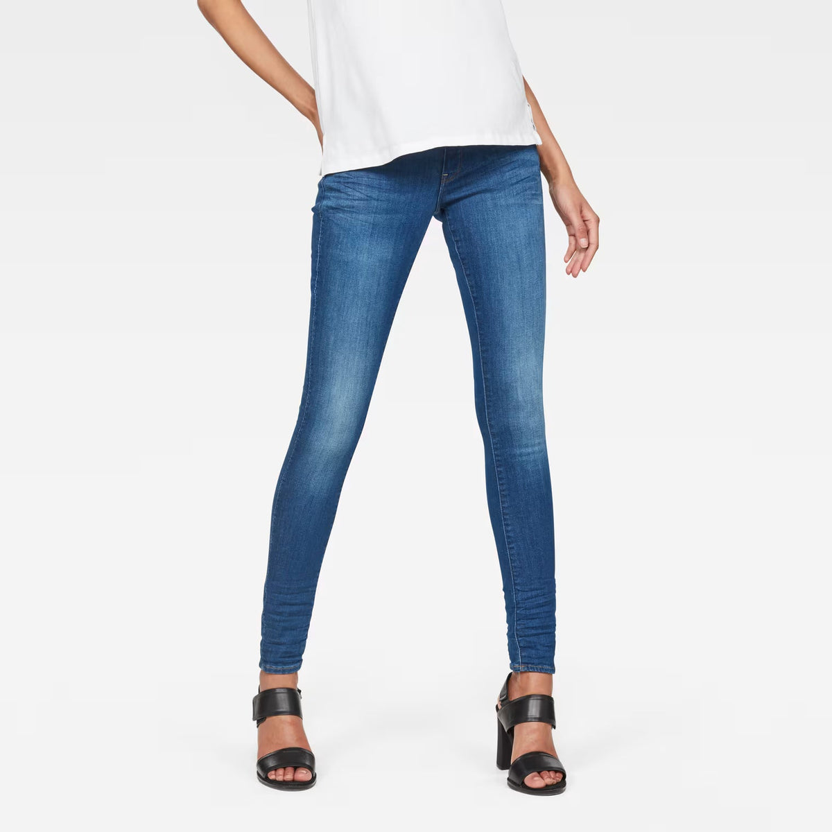 Lifestyle shot of blue skinny jeans with mid waist on a white background
