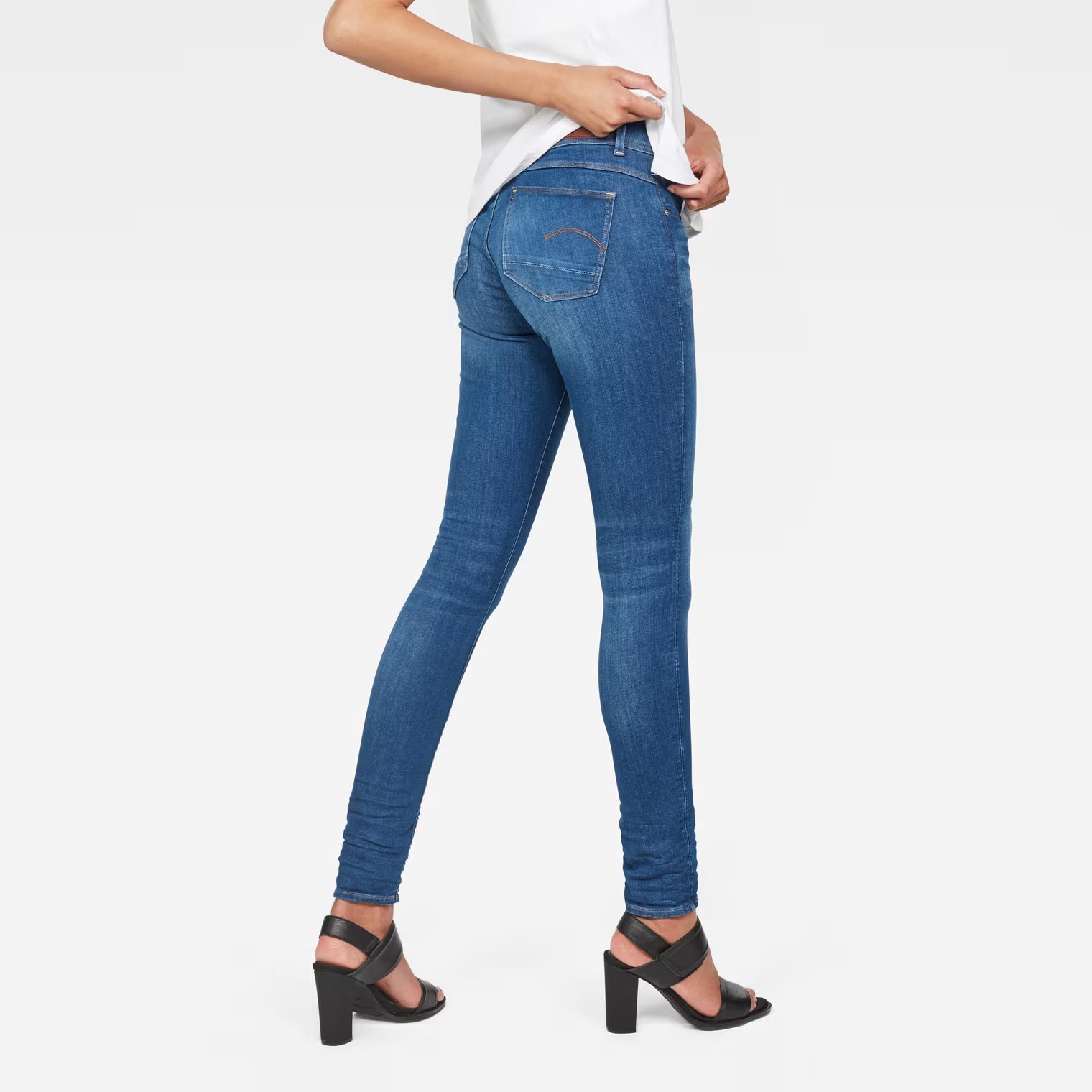 Back view of blue skinny jeans with mid waist on a white background