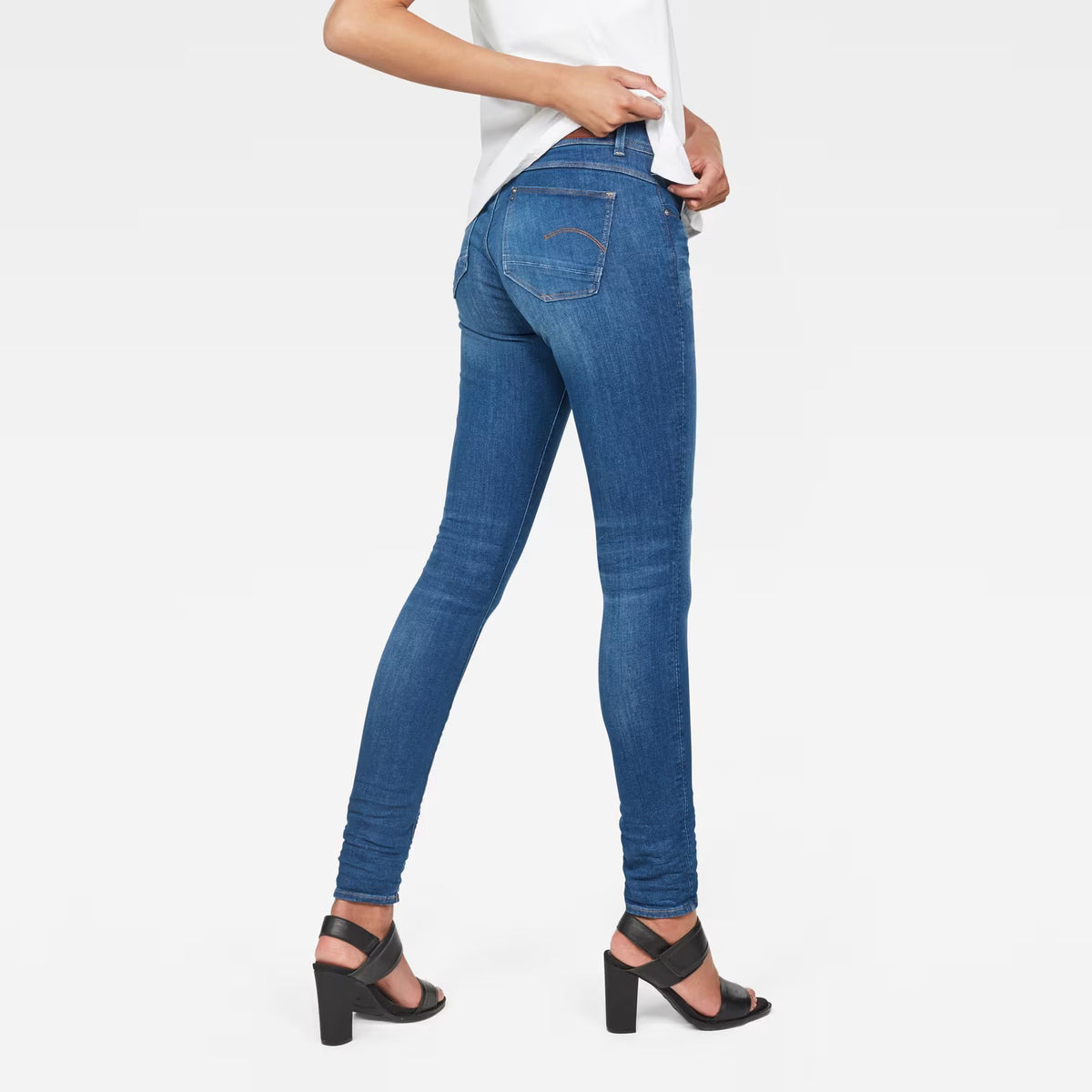 Back view of blue skinny jeans with mid waist on a white background