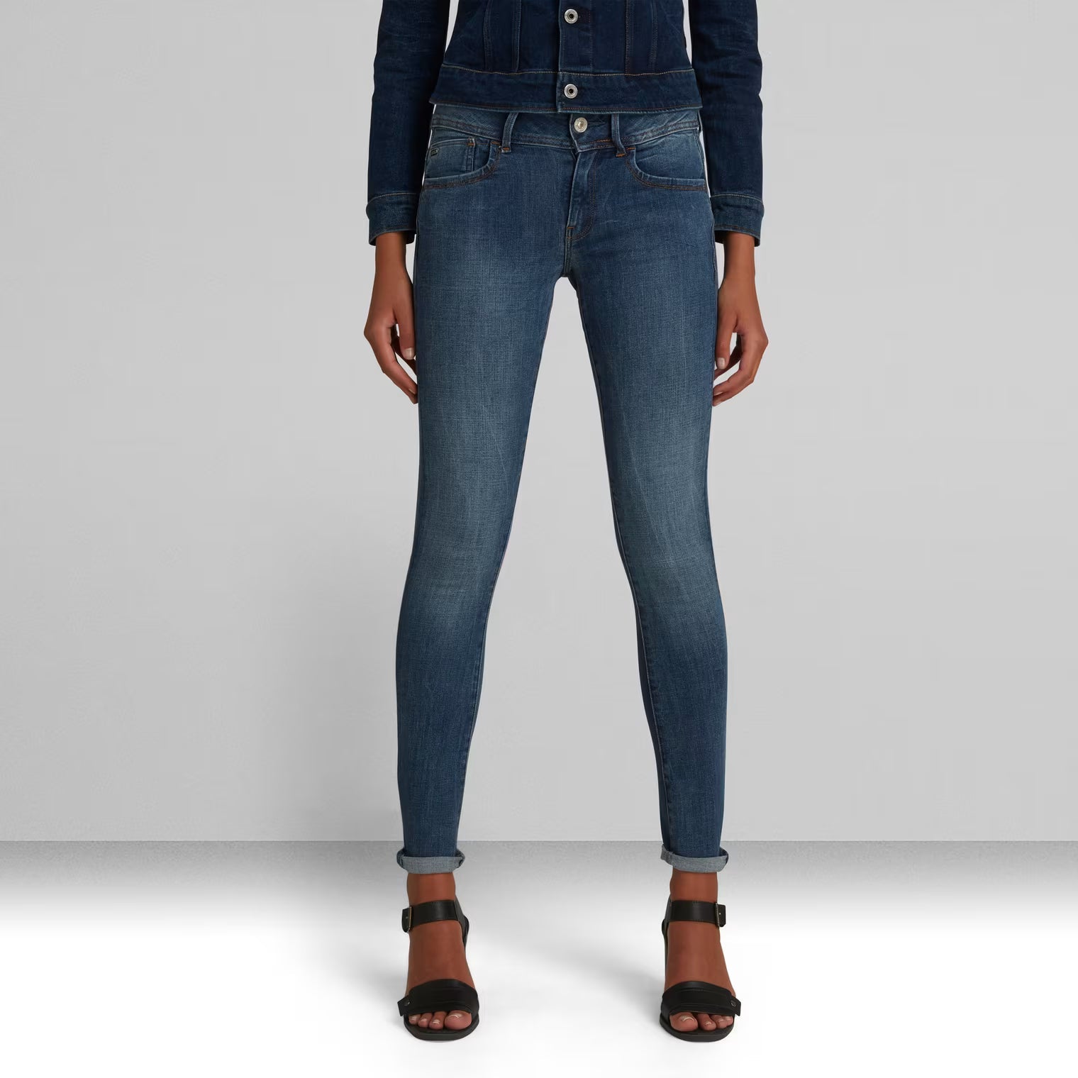 Front view of dark blue skinny jeans featuring a super skinny fit and button closure.
