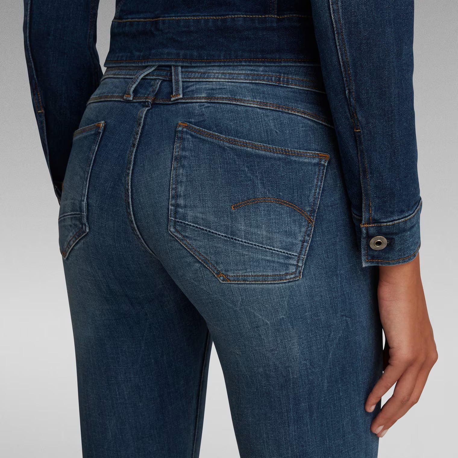 Detail shot of dark blue skinny jeans showcasing stitching details from the back view.