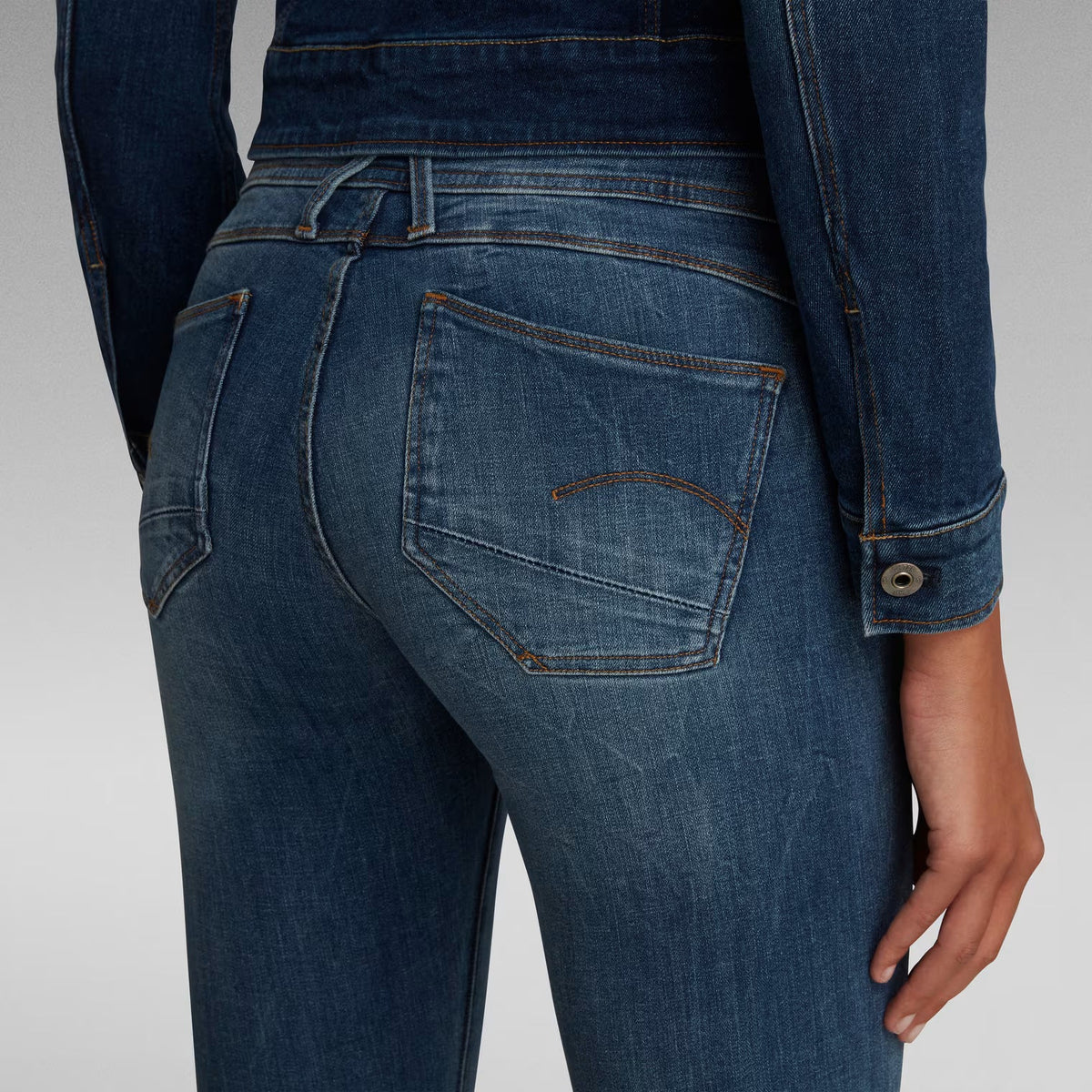 Detail shot of dark blue skinny jeans showcasing stitching details from the back view.