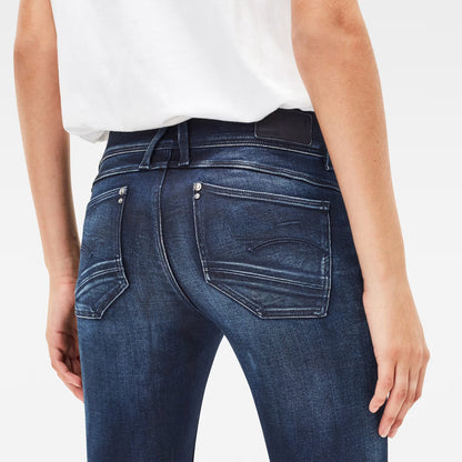 Detail close-up of dark blue skinny jeans highlighting zipper detail and skinny fit on a white background.