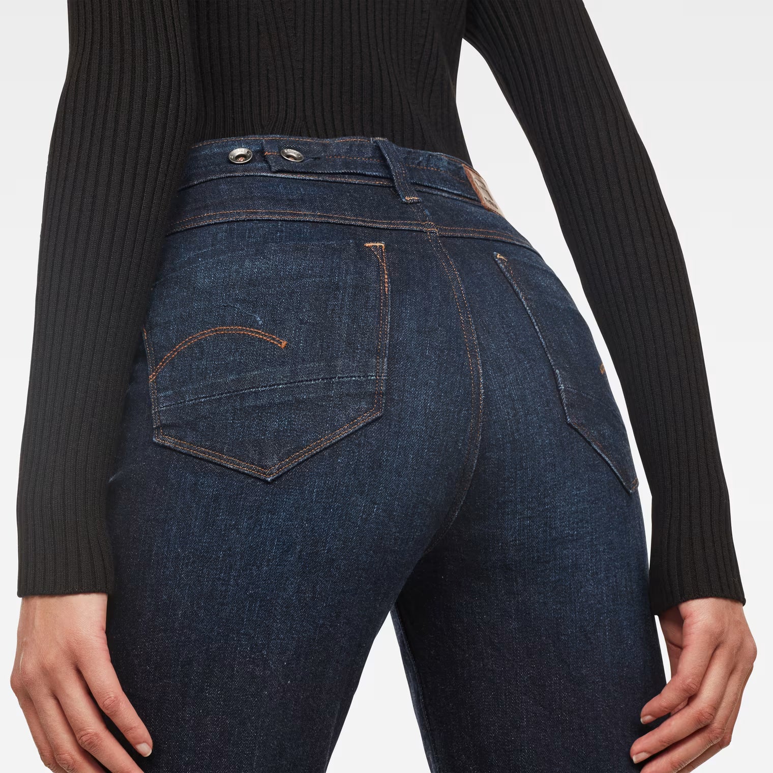 Detail close-up of dark blue high waist straight ankle jeans highlighting back pockets and stitching.