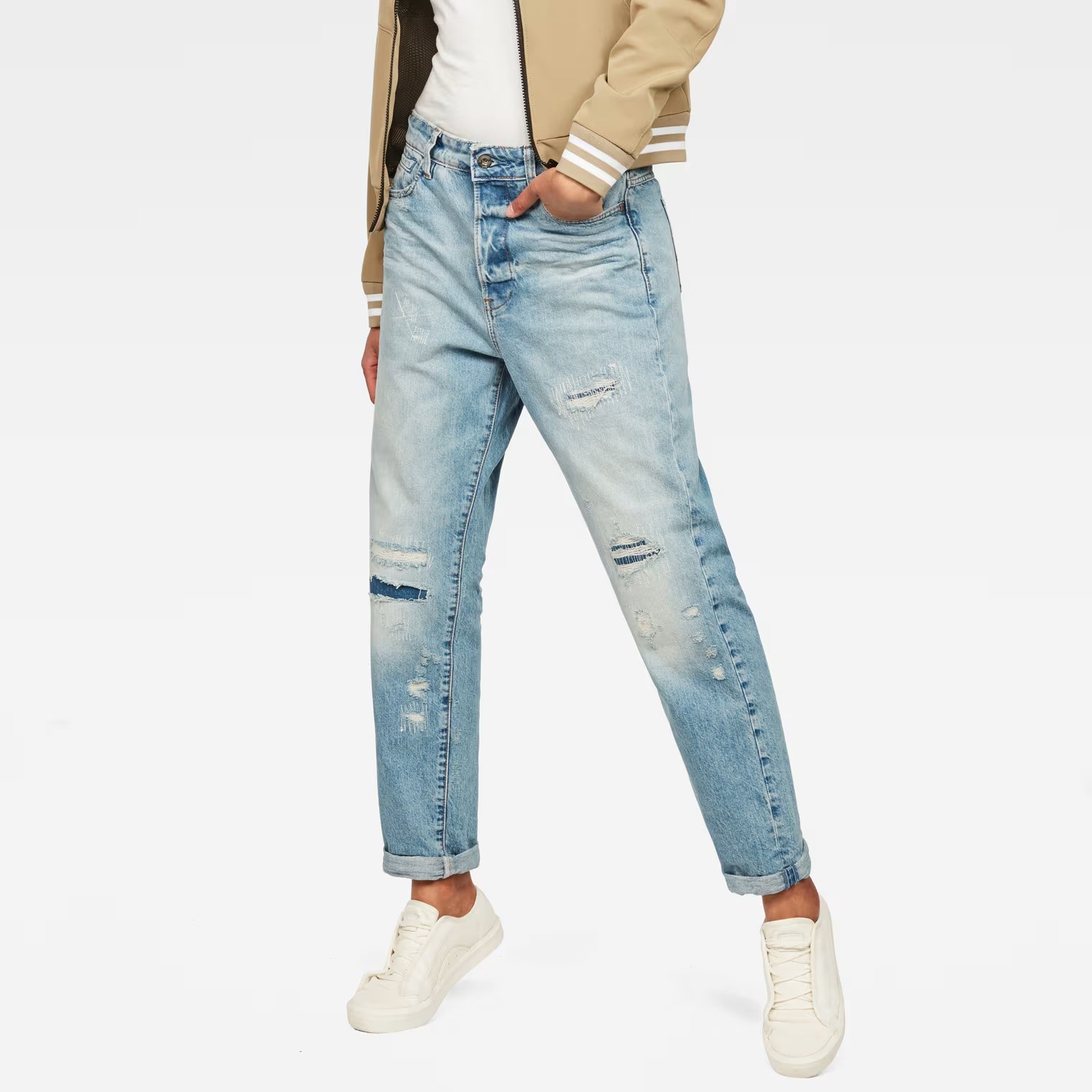 Lifestyle shot of light blue high waist boyfriend jeans with distressed details on a white background.