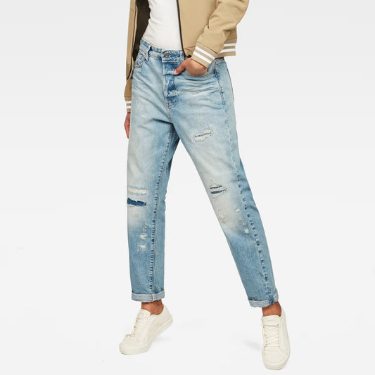 Lifestyle shot of light blue high waist boyfriend jeans with distressed details on a white background.