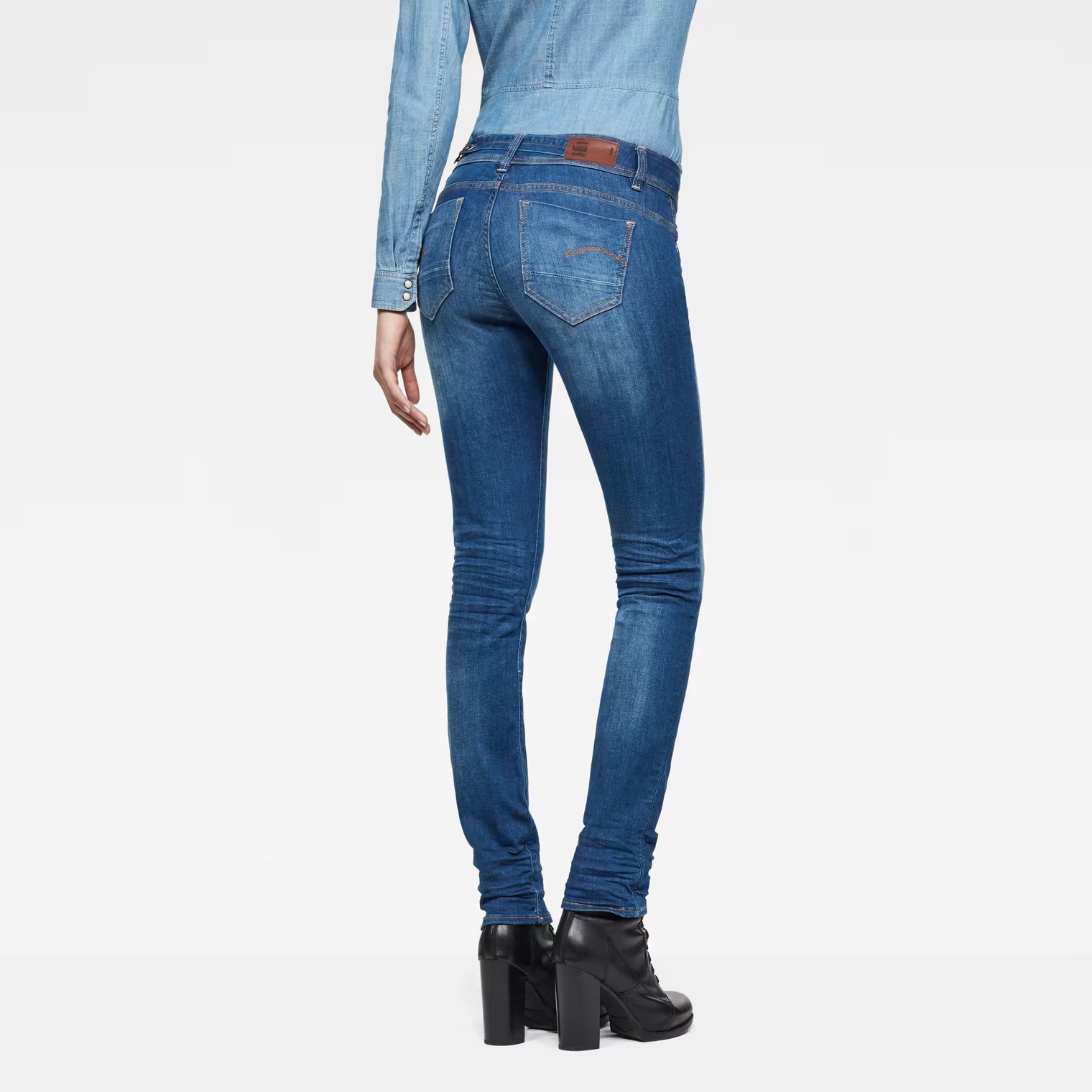 Back view of medium blue jeans showcasing the mid waist and straight fit on a white background.