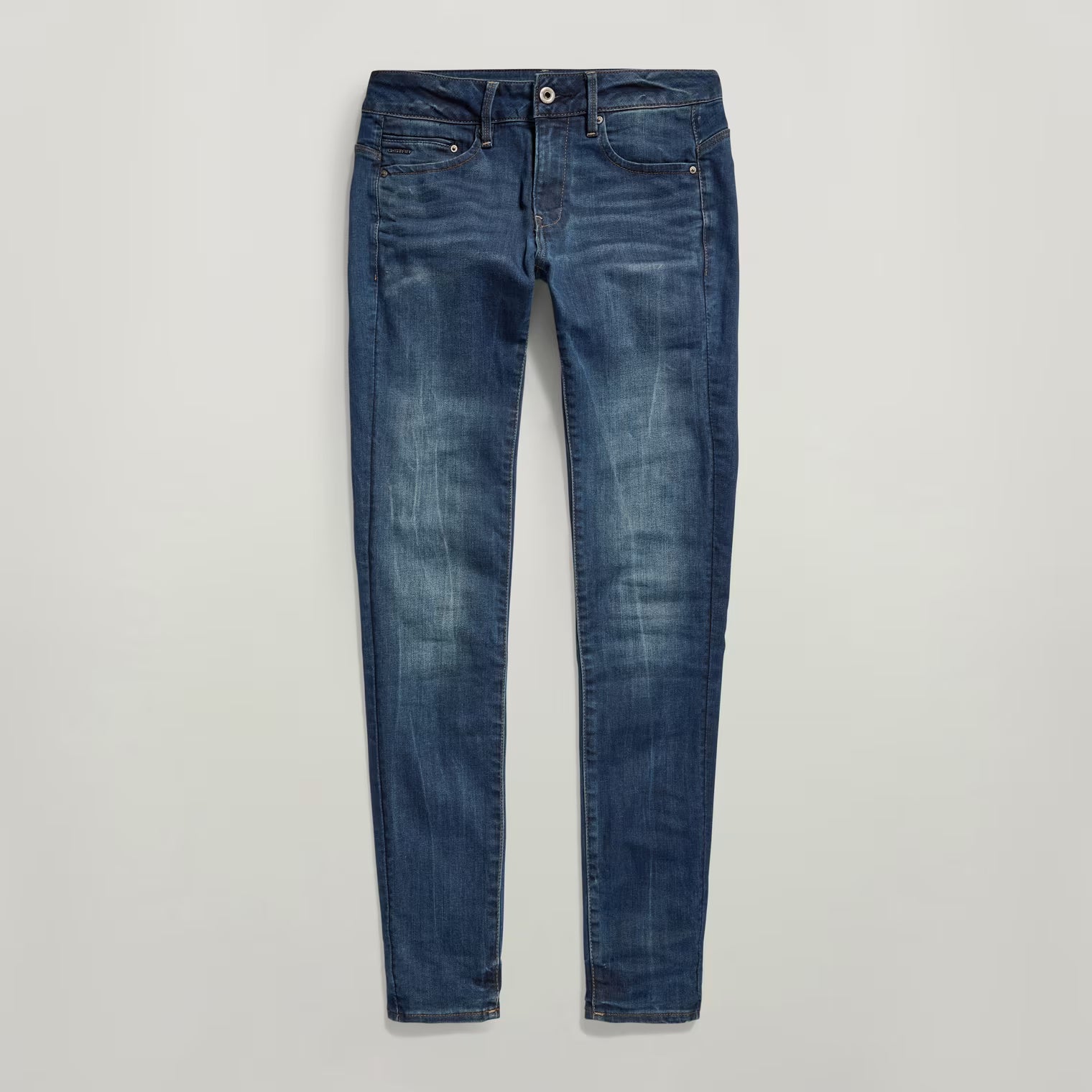 Close-up of dark blue skinny jeans with zipper detail on a white background.