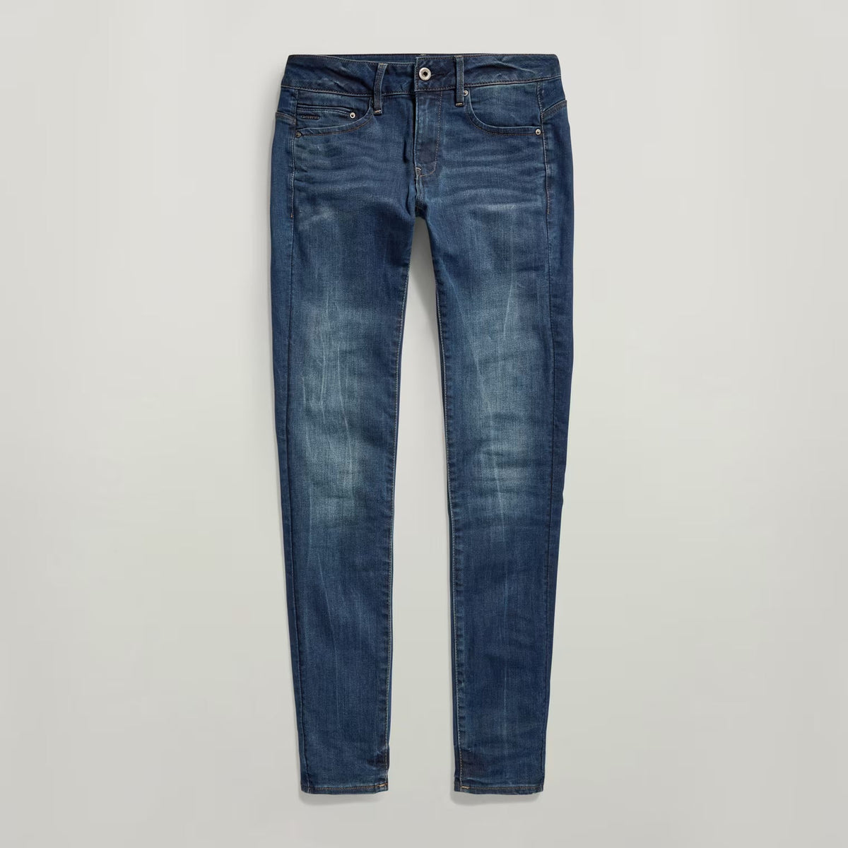 Close-up of dark blue skinny jeans with zipper detail on a white background.
