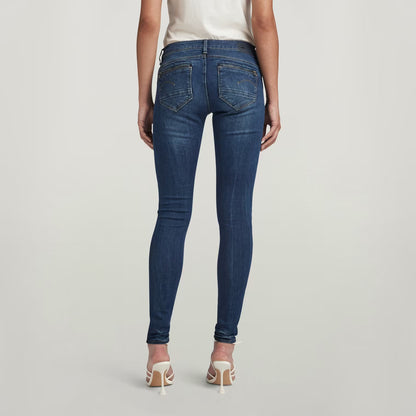Back view of dark blue skinny jeans showcasing the mid waist fit on a white background.