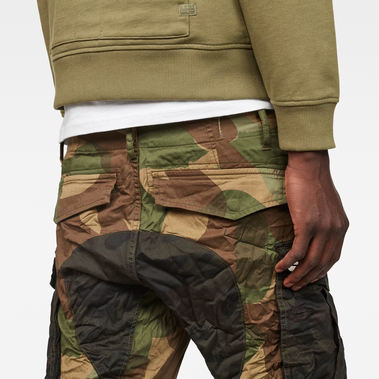 Detail close-up of the green tapered pants highlighting the camouflage pattern and back pockets.