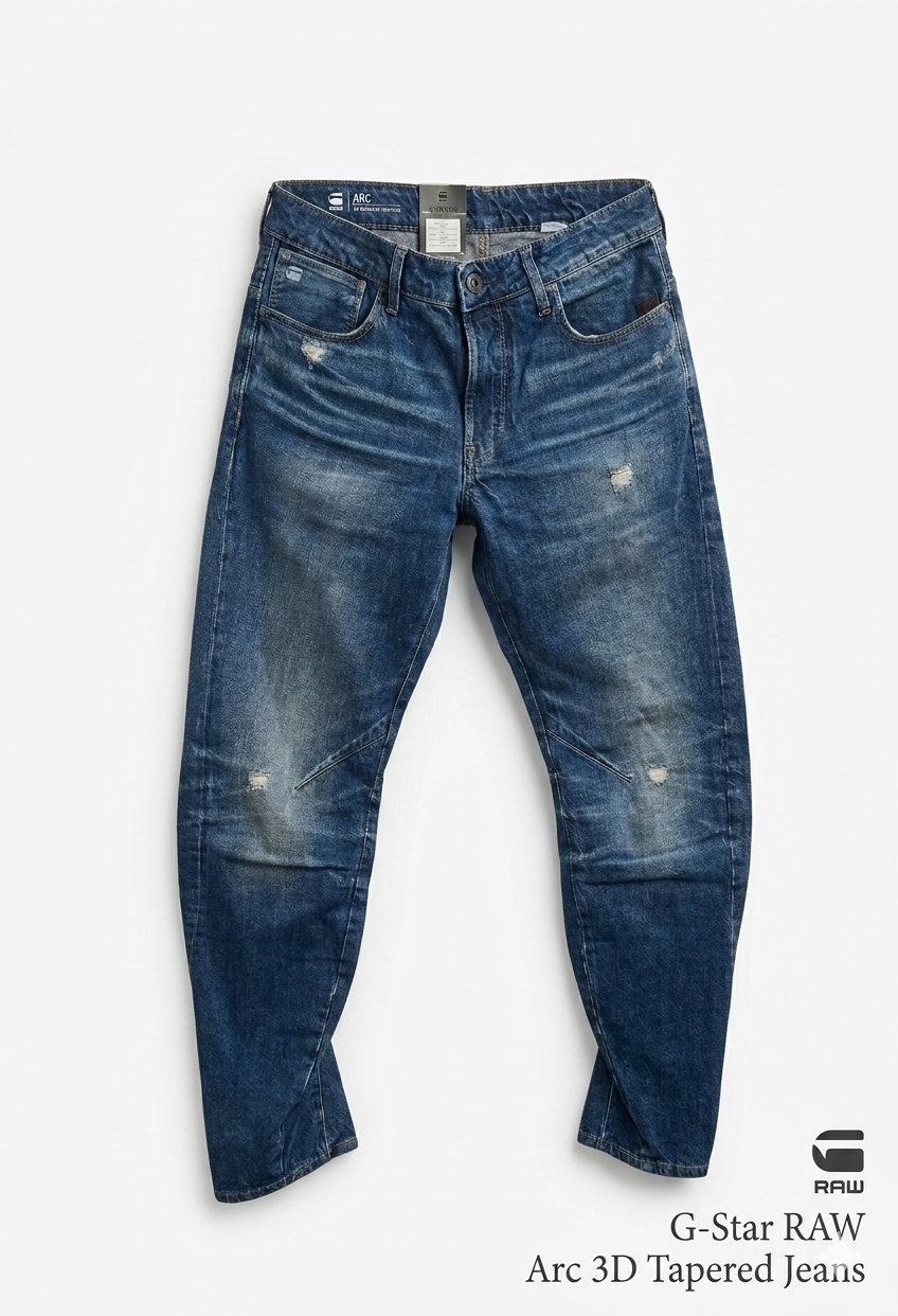 Front view of blue distressed G-Star RAW Arc 3D Tapered Jeans with five pockets on a white background