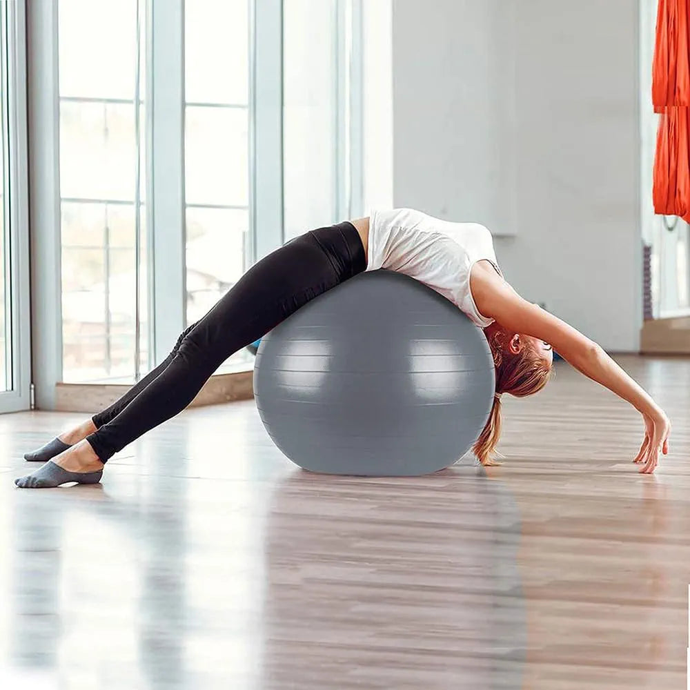 Woman stretching backwards over grey Liveup gym ball in studio