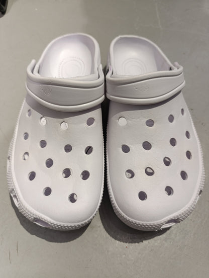 Pair of white foam clogs on a grey floor