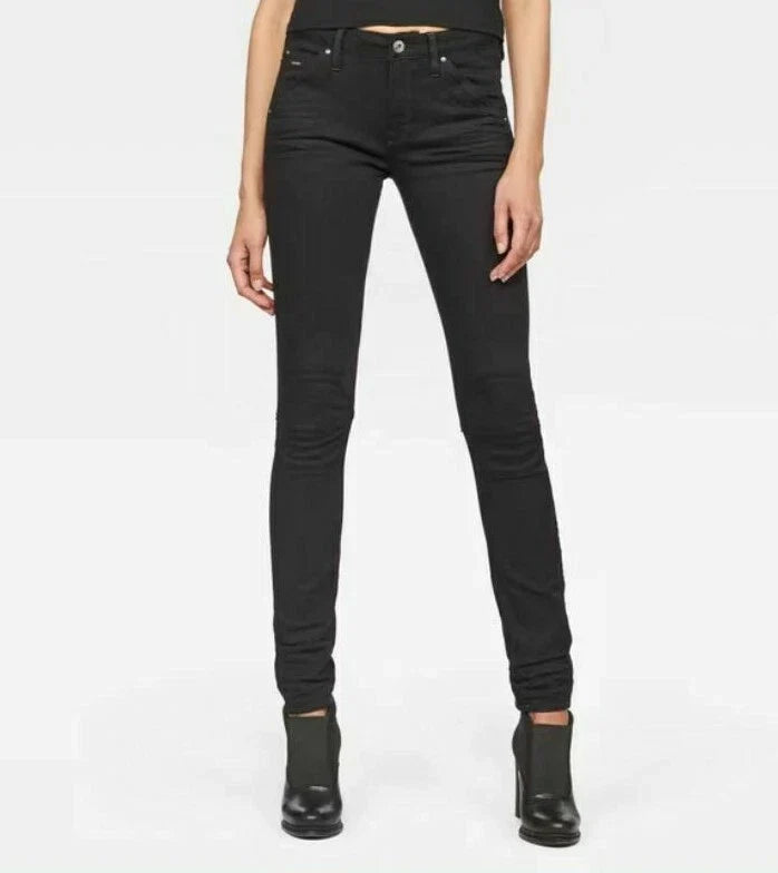 Lifestyle shot of a woman wearing black skinny jeans with a high waist on a white background.