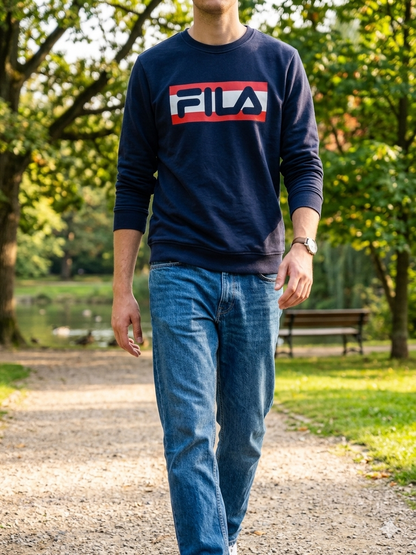 Man walking in a park wearing Fila navy logo sweatshirt