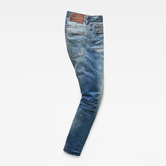 Side view of blue distressed jeans showcasing a slim fit on a white background.