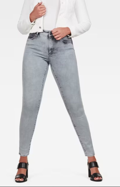 Lifestyle shot of a woman wearing high-waisted gray jeans with a slim fit on a white background.
